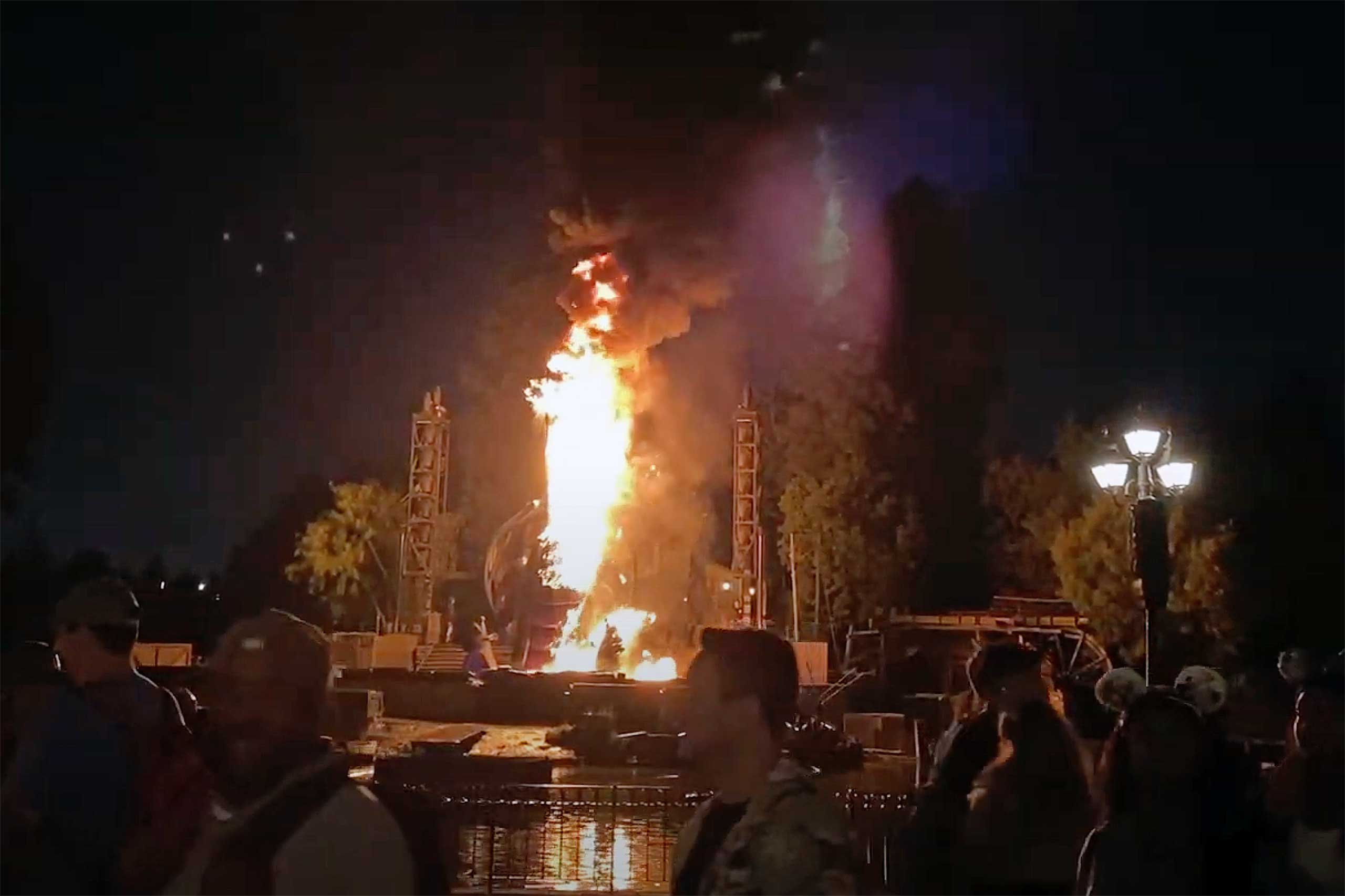 Guests Look on as Flames Shoot From Disney Castle